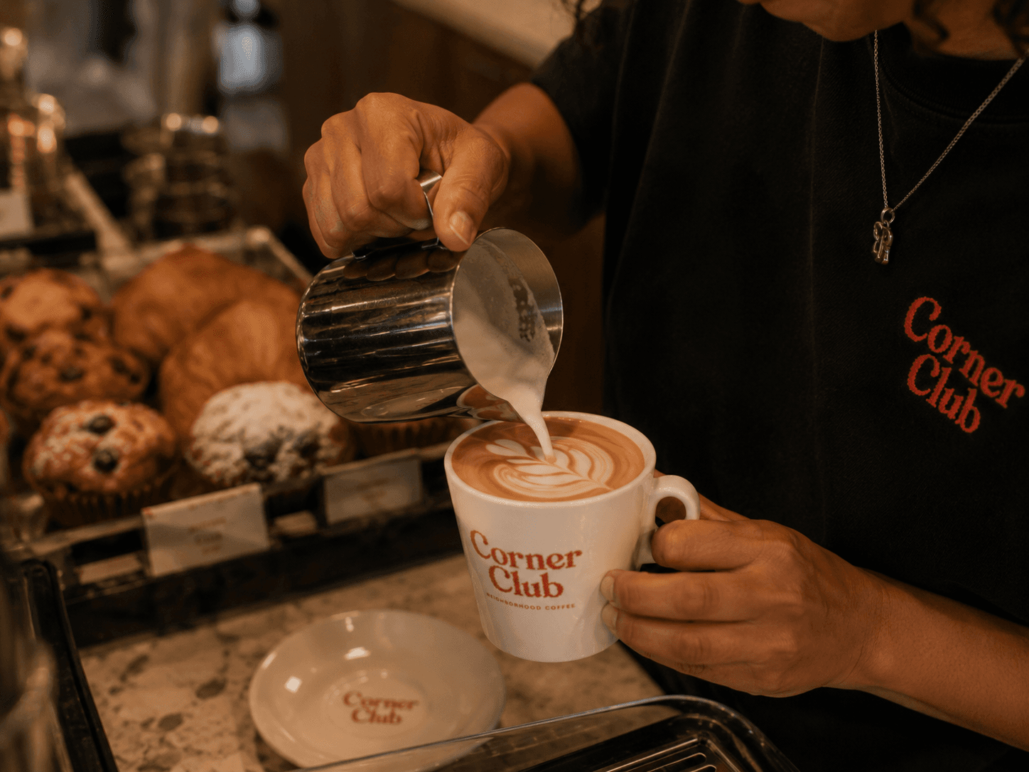 Barista pouring latte art into a Corner Club mug